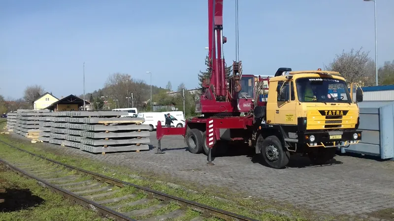 Autojeřáb AD 20T s vysunutými opěrami připravený k práci u složených betonových panelů